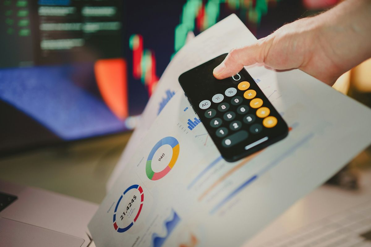 Person som holder en kalkulator over et papir med tall