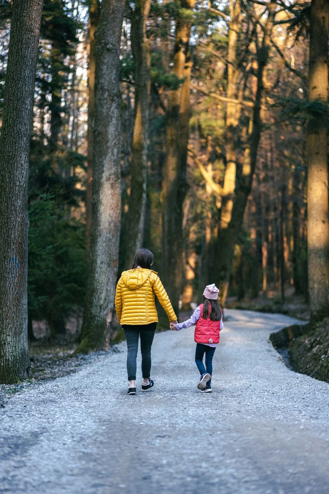 Forelder og barn gar pa sti i skogen